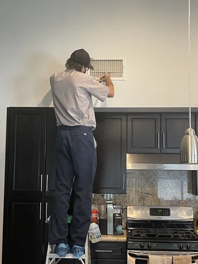 Technician inspecting an air vent during HVAC service in Clarksville
